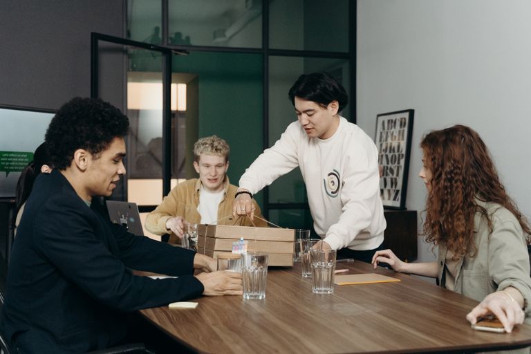 A diverse group of young professionals enjoying a lunch break together in a modern office setting.