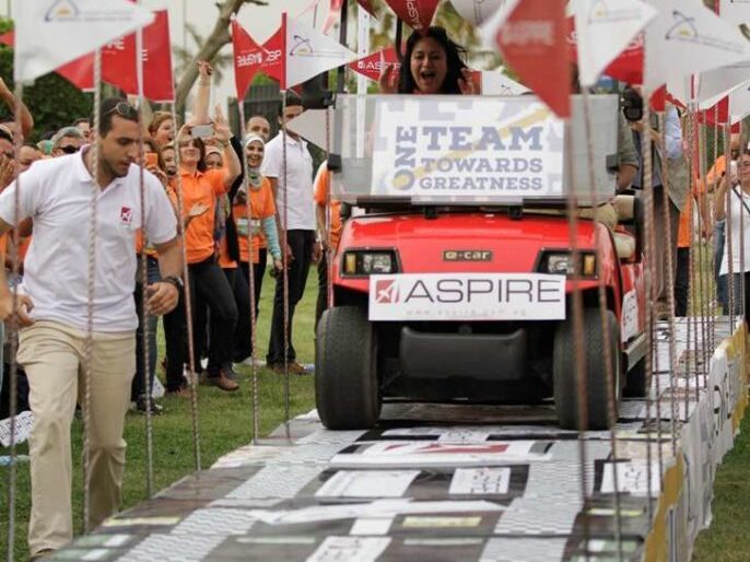 An excited lady driving a small tram with the Aspire logo on the front