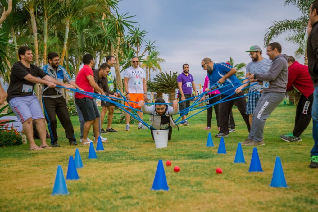 A group of people doing a team-building exercise holding another person up with ropes.